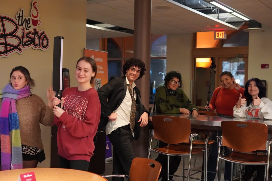 Cast and crew pose for the camera between setups in a cafe