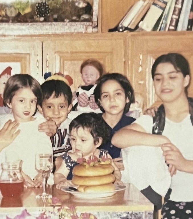 A childhood photograph: Sana Mohtasebzada as a toddler at the center, behind her birthday cake, with her family around her