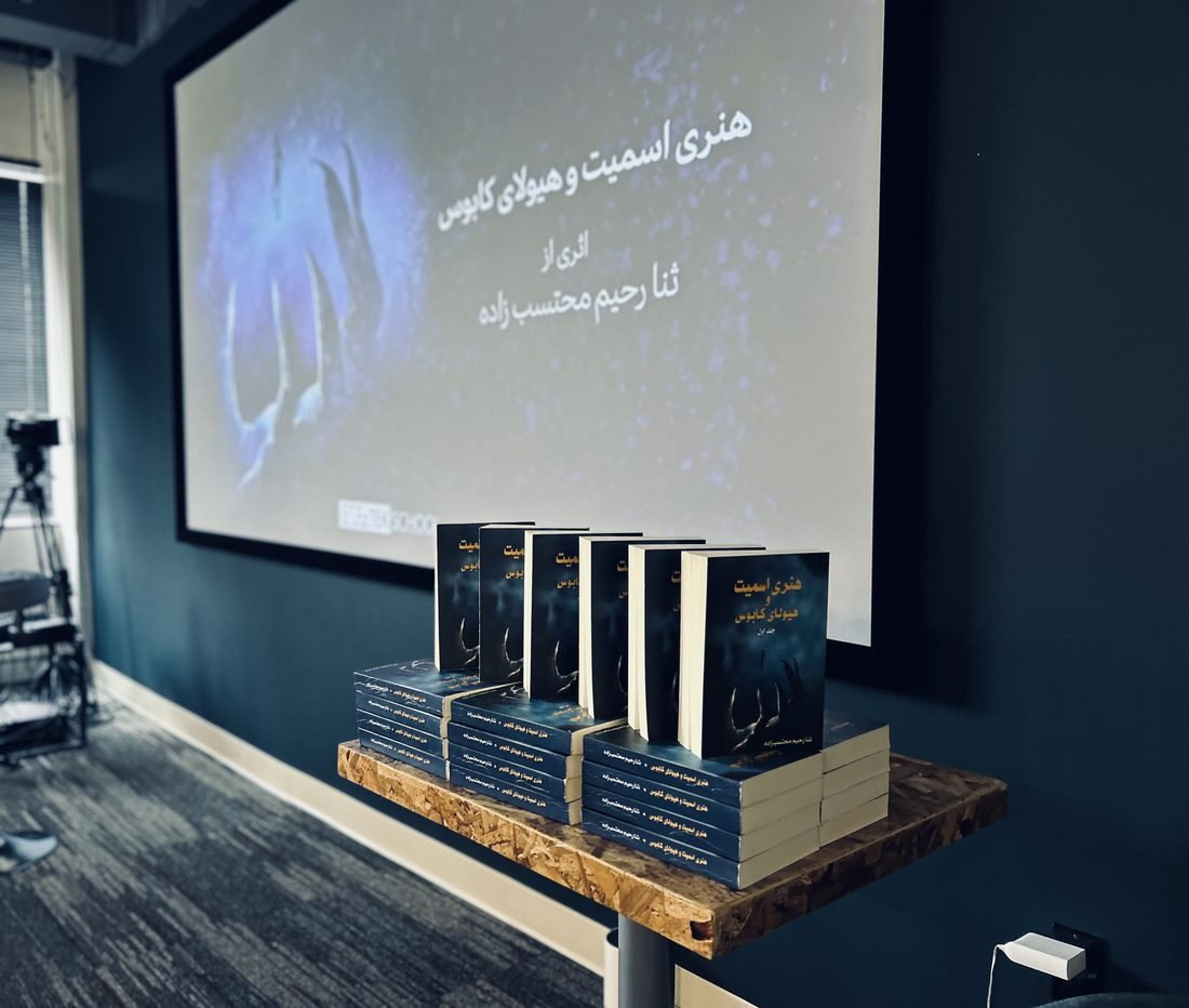Copies of the Persian edition on a table at the launch, with the book shown on a screen behind them