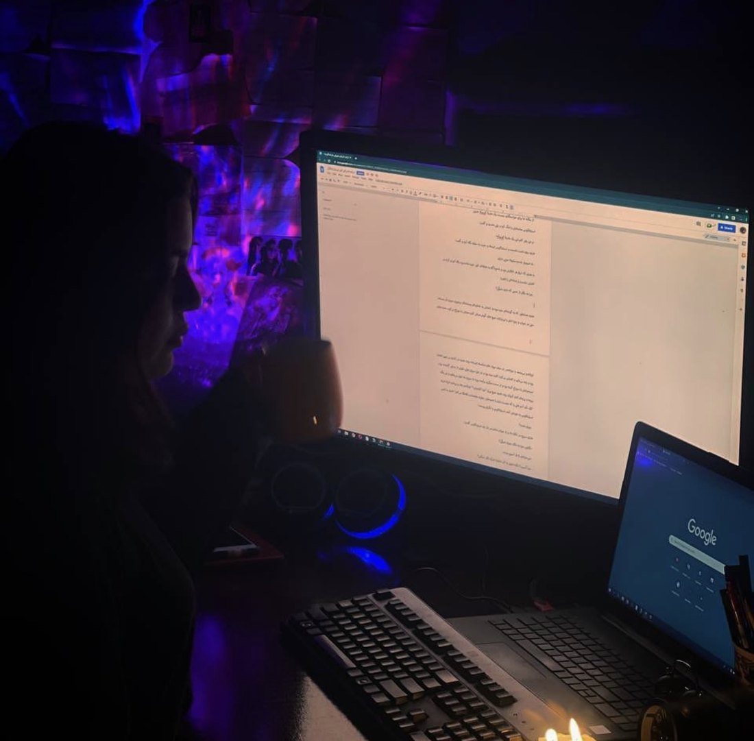 Sana Mohtasebzada in profile in a dark room, lit by a computer screen filled with Persian text